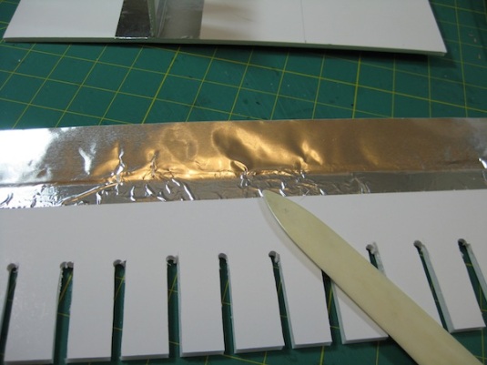 Use a bone folder to fully adhere the metal tape to the support